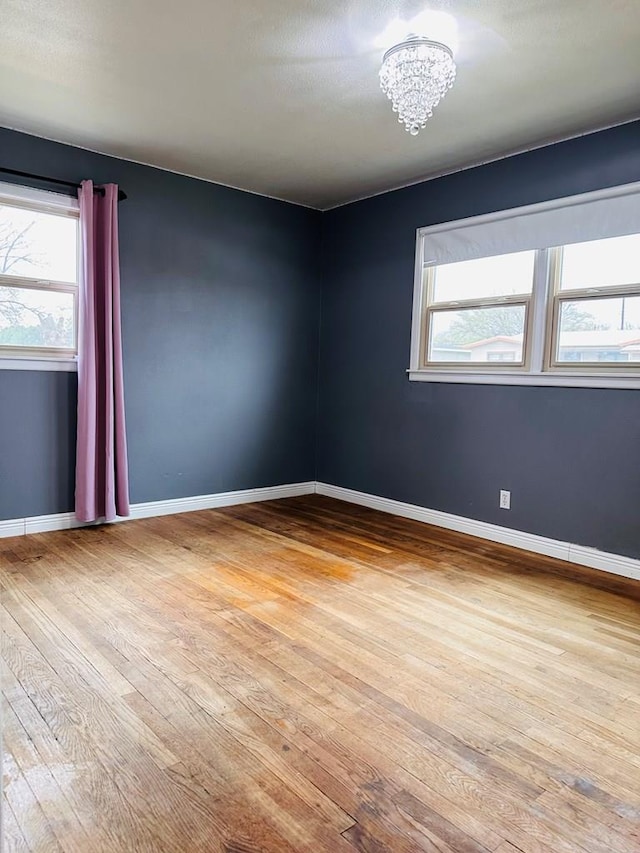 301 SW 11th St, Andrews, TX 79714 - empty room featuring hardwood / wood-style flooring and a chandelier