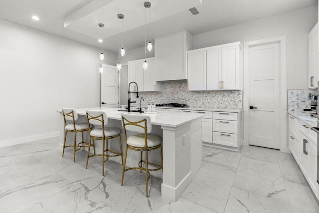 8652 Fiesta Ct, Odessa, TX 79765 - kitchen with light marble finish floors, stainless steel gas stovetop, a center island with sink, recessed lighting, and white cabinetry