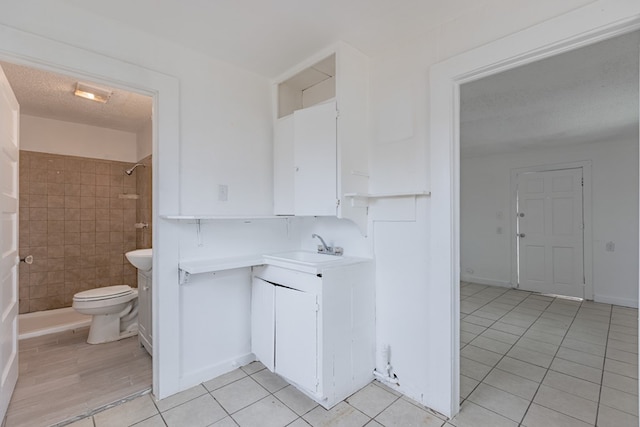 900 N Dotsy Ave, Odessa, TX 79763 - bathroom featuring tile patterned flooring, vanity, a tile shower, and a textured ceiling