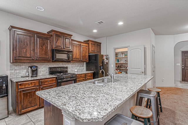 1506 San Miguel Ct, Midland, TX 79705 - kitchen with black appliances, a sink, arched walkways, a kitchen island with sink, and tasteful backsplash