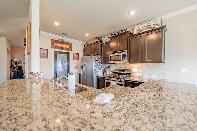 kitchen with light stone countertops, appliances with stainless steel finishes, ornamental molding, dark brown cabinetry, and sink