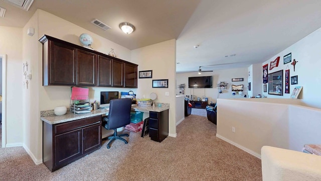 carpeted office space featuring ceiling fan and built in desk