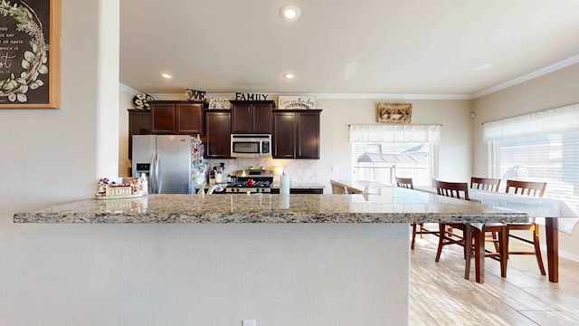 kitchen with backsplash, kitchen peninsula, crown molding, and stainless steel appliances