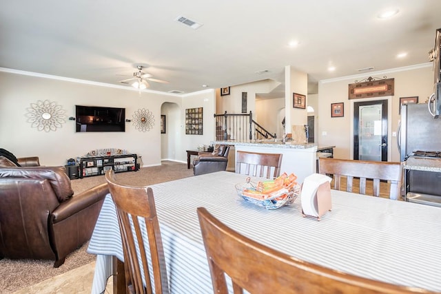 carpeted dining space featuring ceiling fan and ornamental molding