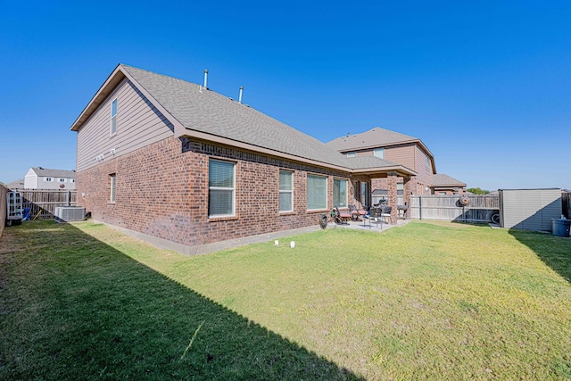 rear view of house with central air condition unit, a lawn, a patio, and a storage unit