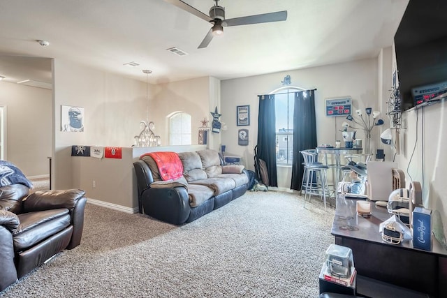 carpeted living room featuring ceiling fan with notable chandelier