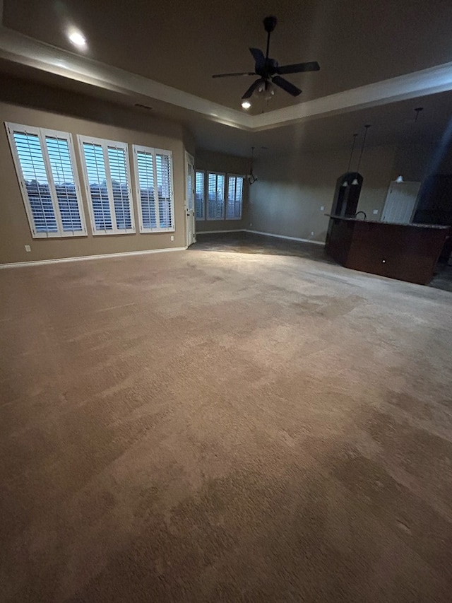 carpeted empty room with ceiling fan and a tray ceiling