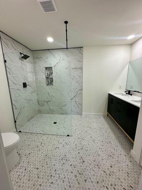 bathroom featuring vanity, toilet, and a tile shower