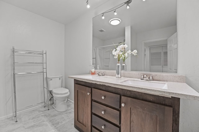 bathroom featuring toilet, a shower with shower curtain, double vanity, and baseboards