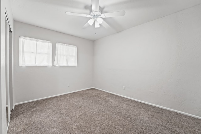 carpeted empty room with ceiling fan and baseboards