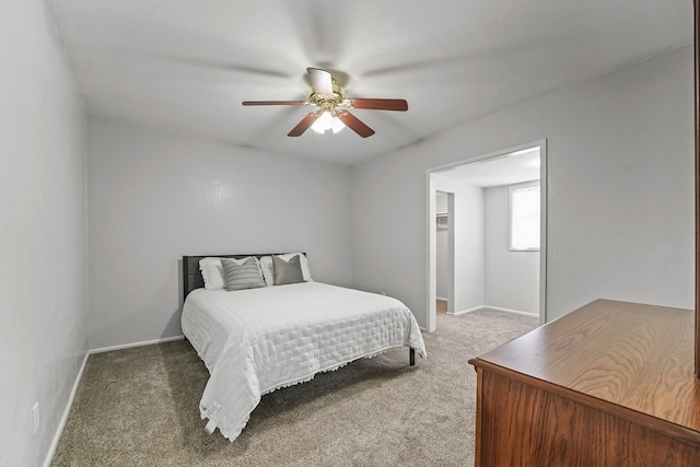 carpeted bedroom with baseboards, a ceiling fan, and a walk in closet