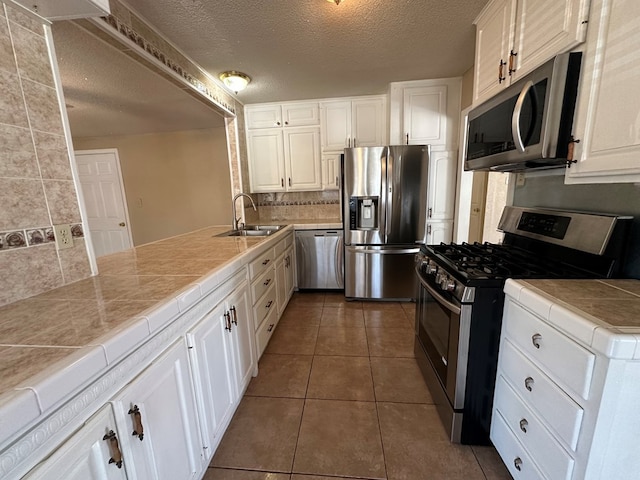 902 W 39th St, Odessa, TX 79764 - kitchen with appliances with stainless steel finishes, tile countertops, tasteful backsplash, a textured ceiling, and white cabinetry