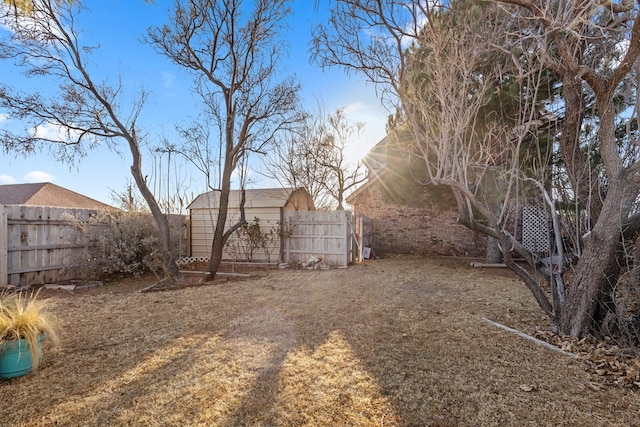 view of yard featuring an outbuilding, a fenced backyard, and a storage shed