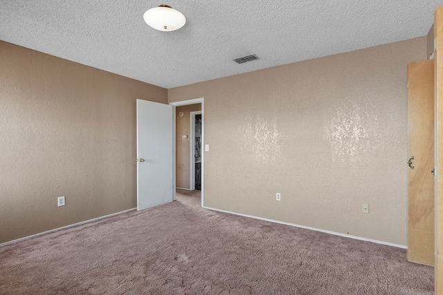 carpeted spare room featuring visible vents, a textured wall, and a textured ceiling