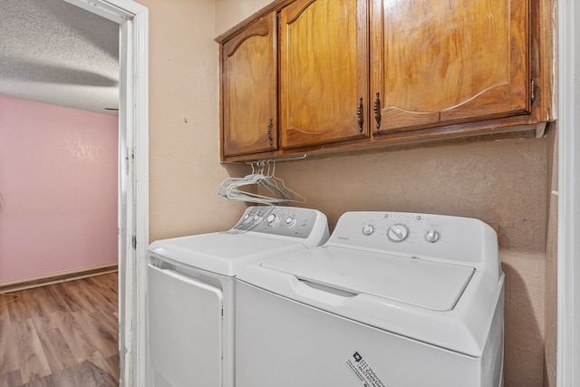 washroom with cabinet space, light wood-style flooring, baseboards, and washer and clothes dryer