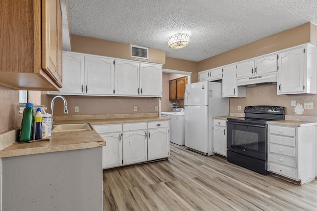 kitchen with freestanding refrigerator, under cabinet range hood, black range with electric cooktop, white cabinetry, and a sink