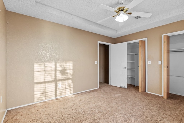 unfurnished bedroom with carpet, two closets, a ceiling fan, a textured ceiling, and baseboards