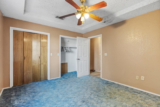 unfurnished bedroom with visible vents, carpet flooring, a textured ceiling, and two closets