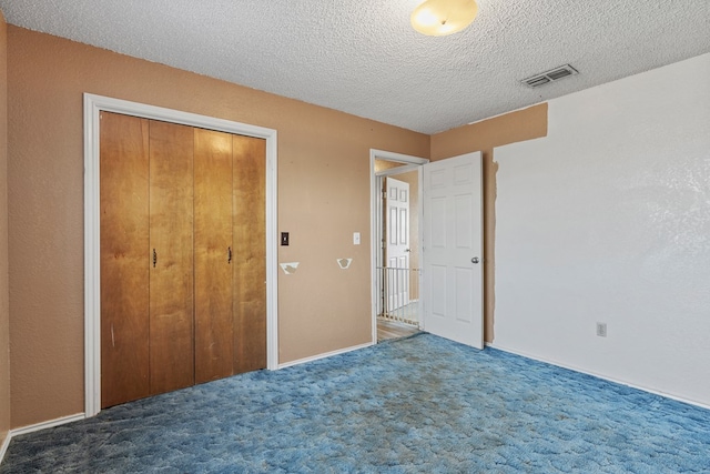 unfurnished bedroom with a closet, visible vents, dark carpet, and a textured ceiling