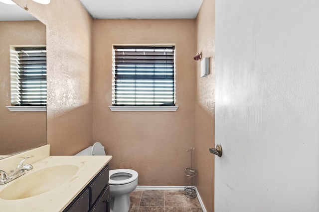 half bath with tile patterned flooring, vanity, toilet, and baseboards