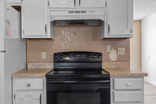 kitchen featuring black / electric stove, under cabinet range hood, white cabinets, light countertops, and freestanding refrigerator