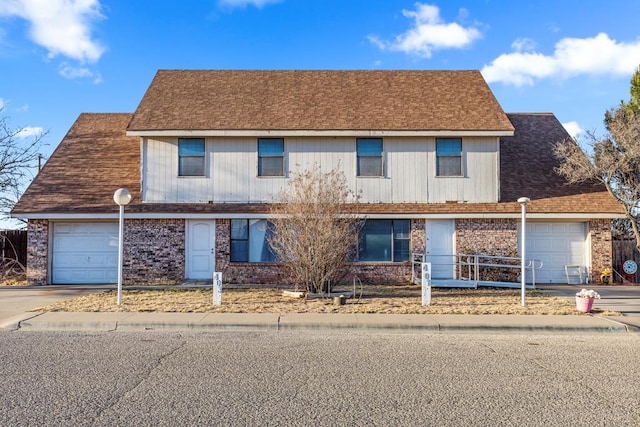 view of front facade with concrete driveway, roof with shingles, brick siding, and an attached garage