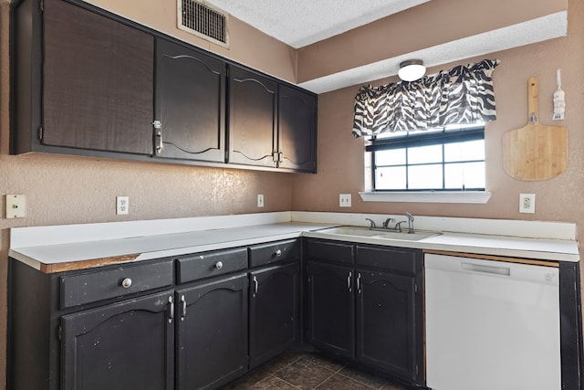 kitchen featuring a textured ceiling, a sink, visible vents, light countertops, and dishwasher