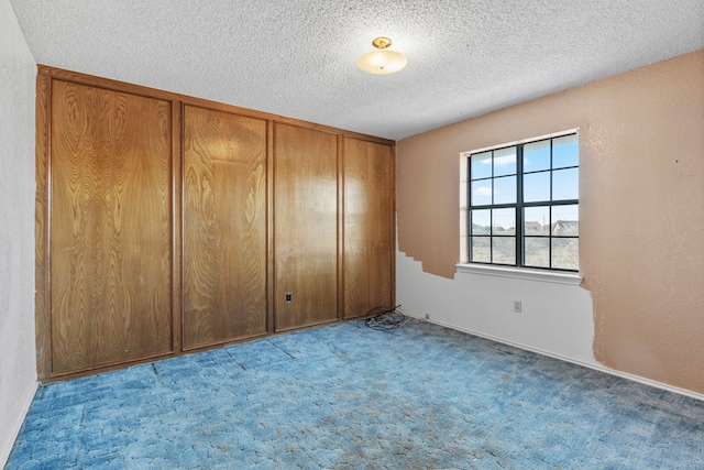 unfurnished room with a textured ceiling and light colored carpet