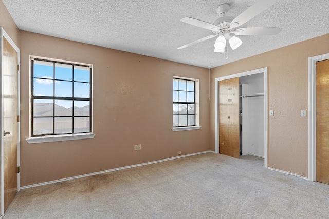 unfurnished bedroom with a ceiling fan, light colored carpet, a textured wall, and a textured ceiling