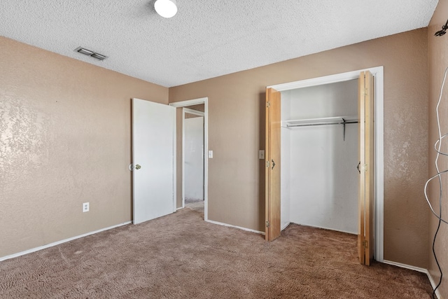 unfurnished bedroom featuring a closet, visible vents, a textured ceiling, and carpet flooring