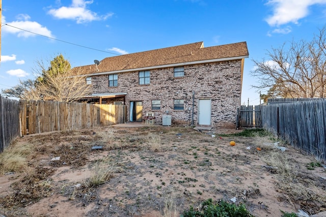 back of house featuring a fenced backyard and brick siding