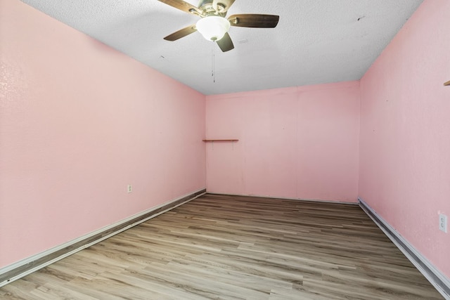 empty room with a ceiling fan, a textured ceiling, baseboards, and wood finished floors