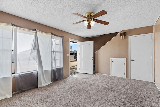 unfurnished room with carpet flooring, ceiling fan, and a textured ceiling