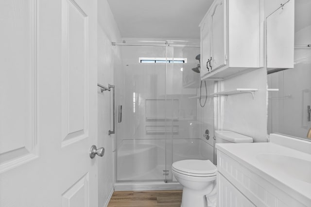 bathroom with wood finished floors, a stall shower, vanity, and toilet