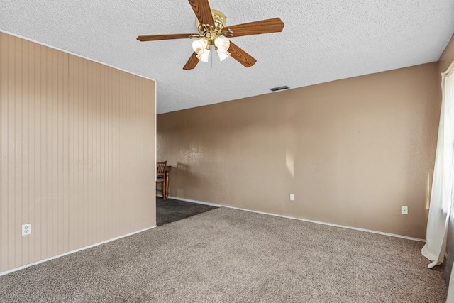 spare room with carpet, visible vents, ceiling fan, and a textured ceiling