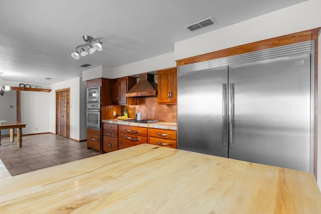 9408 Cromwell Ter, Odessa, TX 79764 - kitchen featuring built in appliances, brown cabinetry, visible vents, decorative backsplash, and wall chimney exhaust hood