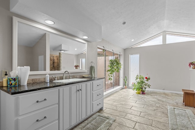 9408 Cromwell Ter, Odessa, TX 79764 - full bath featuring lofted ceiling, vanity, a textured ceiling, stone tile floors, and baseboards
