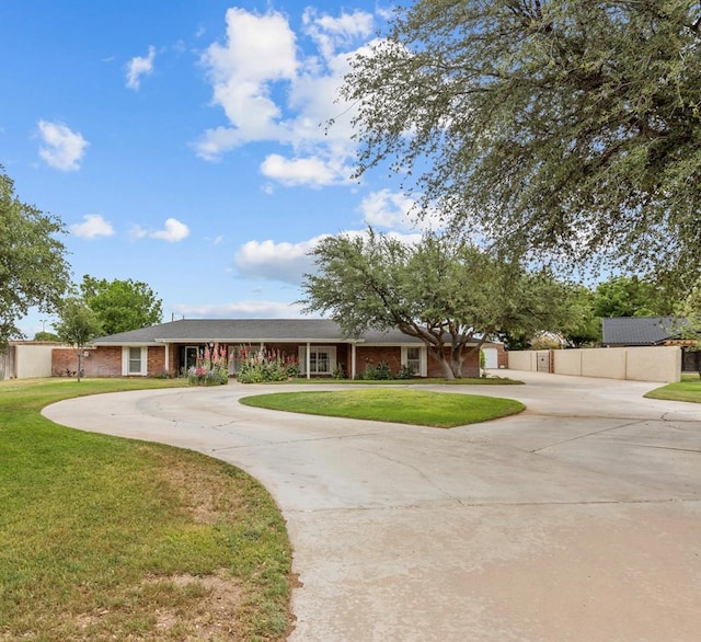 9408 Cromwell Ter, Odessa, TX 79764 - ranch-style house featuring a front lawn, curved driveway, and fence