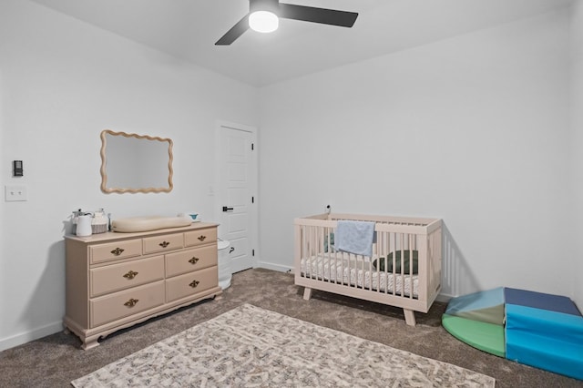 carpeted bedroom featuring baseboards, a crib, and ceiling fan
