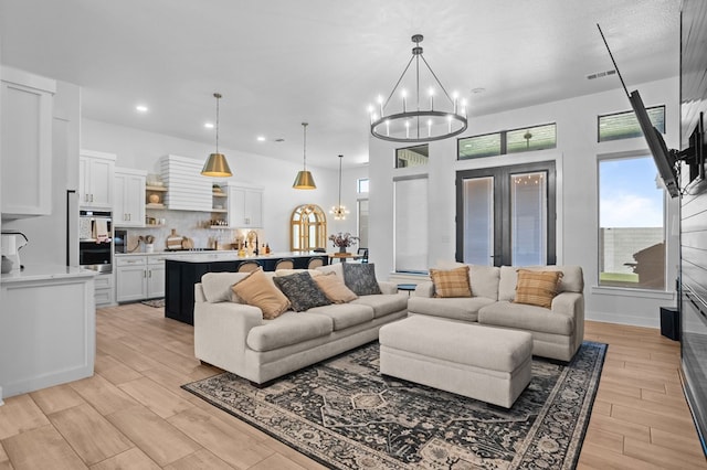 living area featuring recessed lighting, a notable chandelier, plenty of natural light, and light wood-type flooring