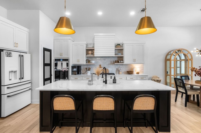 kitchen with decorative backsplash, open shelves, white cabinetry, double oven, and high end fridge