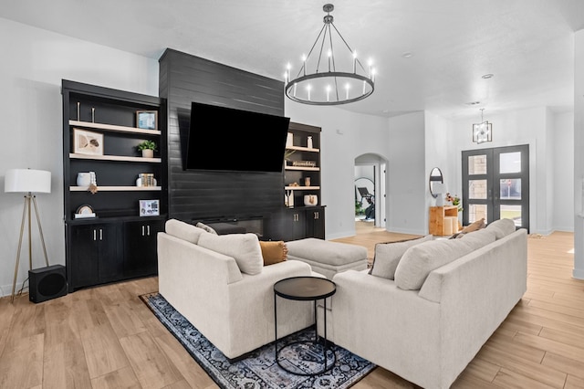 living room with an inviting chandelier, arched walkways, baseboards, and light wood-type flooring