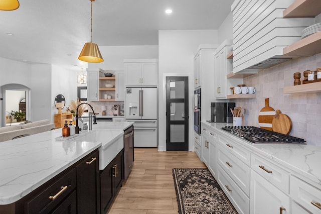 kitchen with a sink, appliances with stainless steel finishes, open shelves, and white cabinetry
