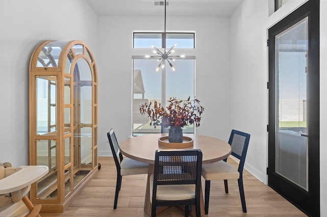dining space featuring light wood-style floors, baseboards, french doors, and a notable chandelier