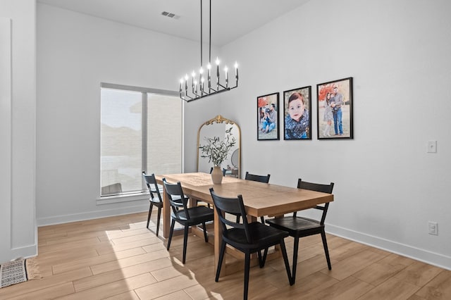 dining space featuring light wood-style floors, baseboards, visible vents, and an inviting chandelier