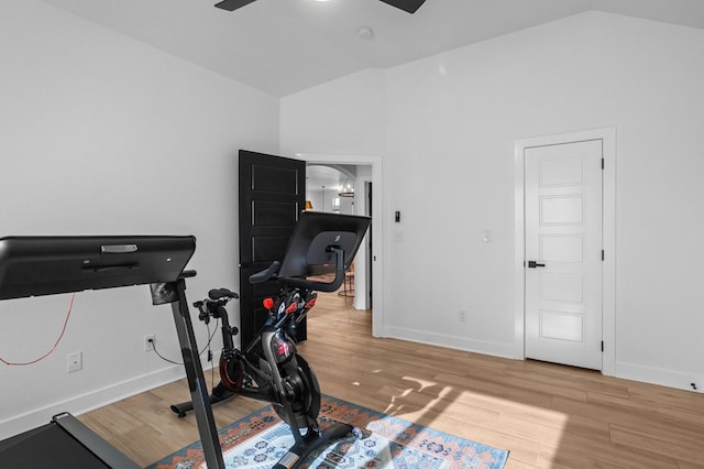exercise room featuring a ceiling fan, baseboards, wood finished floors, and lofted ceiling