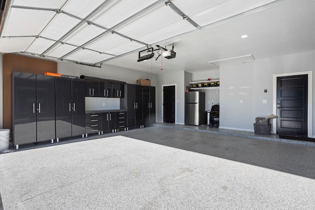 garage with baseboards, a garage door opener, and freestanding refrigerator