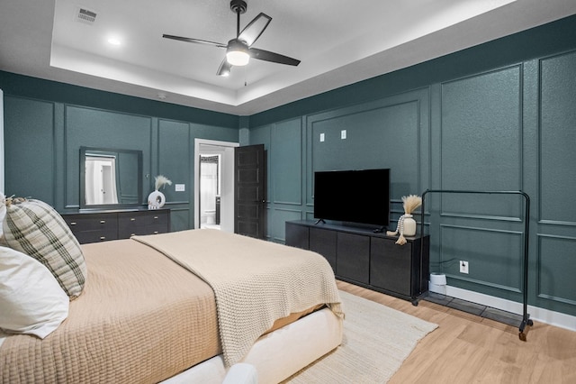 bedroom with visible vents, light wood-style flooring, and a decorative wall
