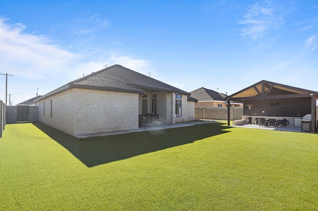 rear view of house with roof with shingles, brick siding, a fenced backyard, a patio area, and a yard