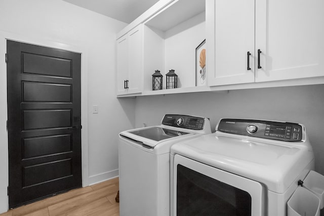 laundry room with baseboards, washer and clothes dryer, light wood finished floors, and cabinet space